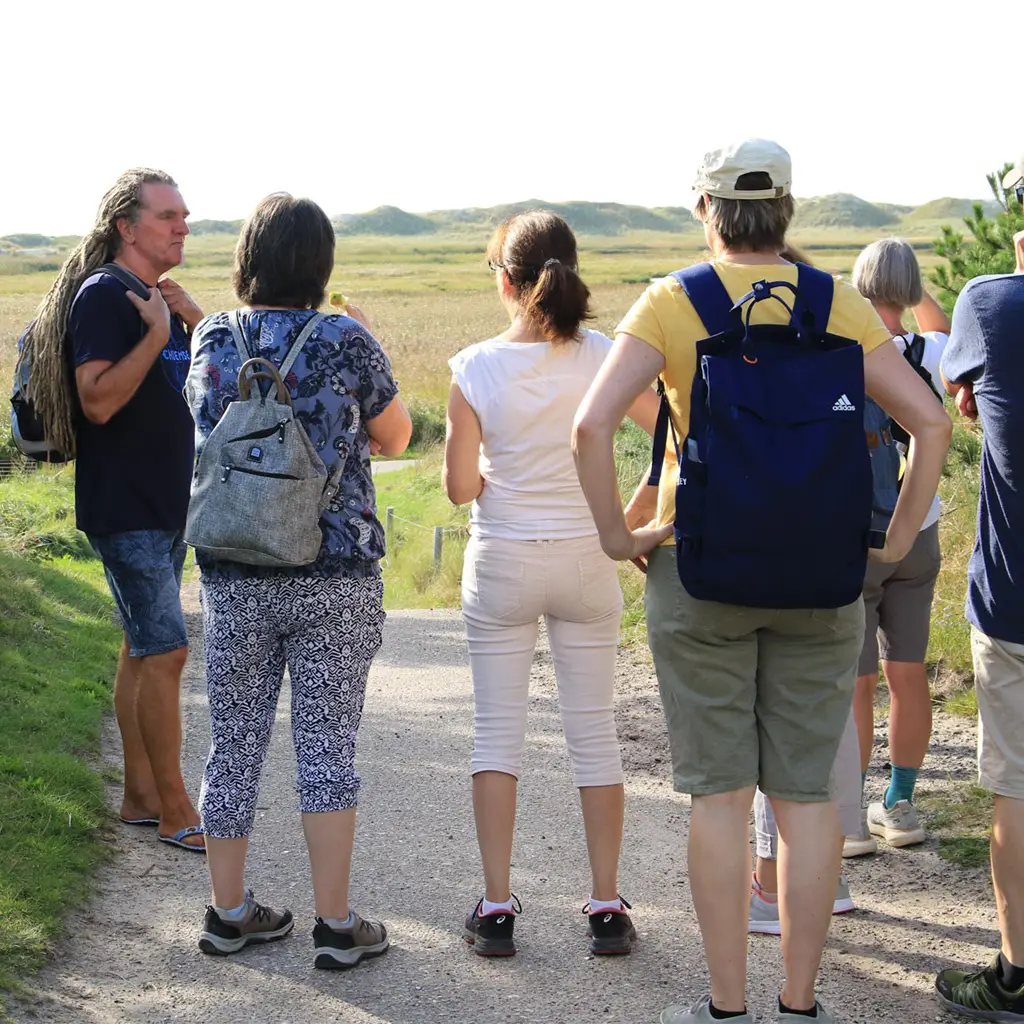 Naturspaziergang in St. Peter-Ording – Gruppe hört dem Guide zu und blickt über die weite Dünen- und Salzwiesenlandschaft