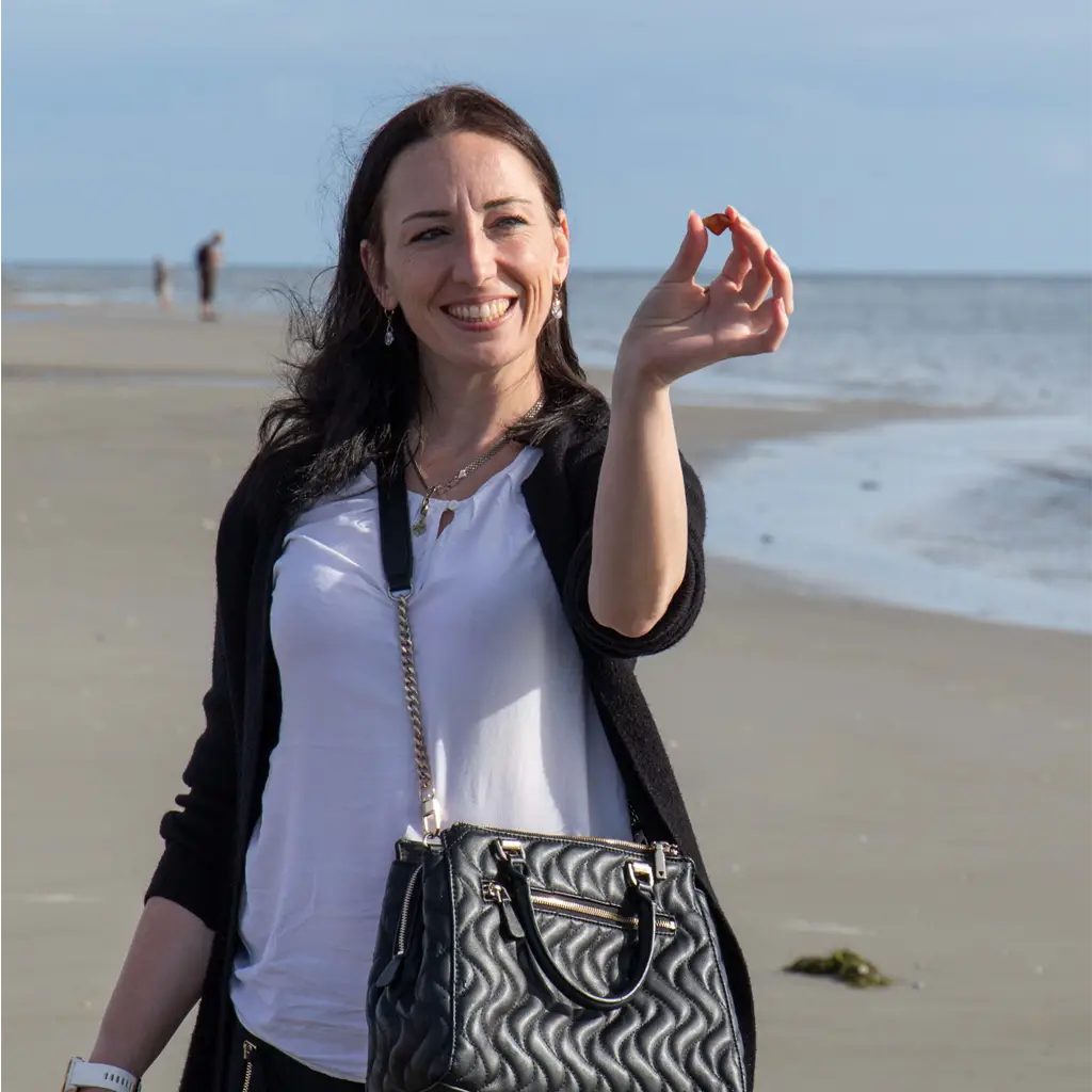 Teilnehmende Person zeigt einen gefundenen Bernstein am Strand von St. Peter-Ording